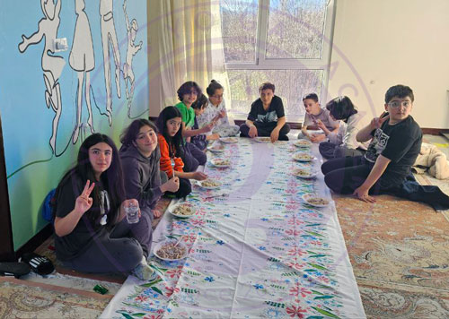گروهی از نوجوانان در سفر یوگیانه دور سفره روی زمین
